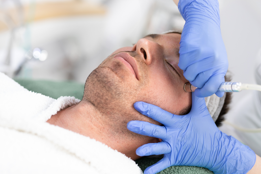 Cosmetologist,Is,Lifting,Laser,Rejuvenation,Device,Under,Male,Face,At